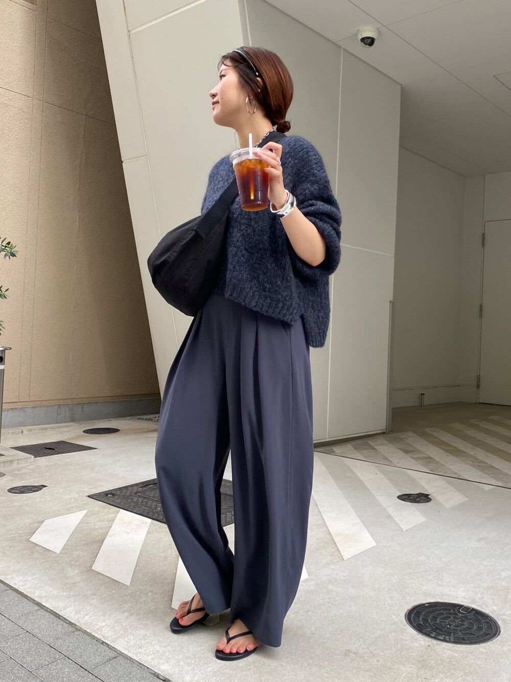 グレー系のニット/セーター、グレー系のスラックス、ブラック系のショルダーバッグを着用したレディースの秋コーディネートの4枚目の写真