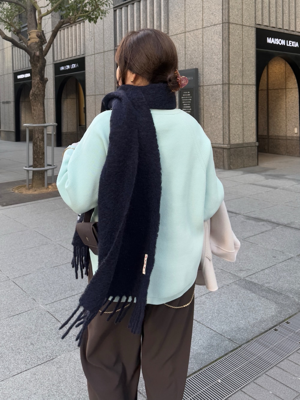 グリーン系のニット/セーター、ブラウン系のスラックス、グレー系のTシャツ/カットソーを着用したレディースの冬コーディネートの4枚目の写真