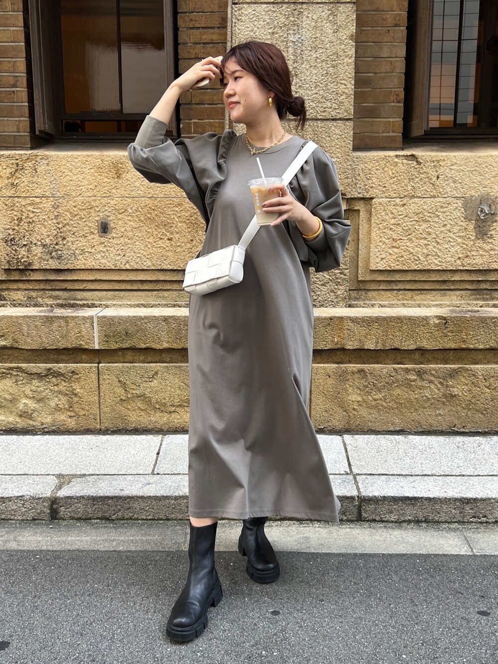 ブラウン系のワンピース、ホワイト系のショルダーバッグ、ブラック系のブーツを着用したレディースの秋コーディネートの2枚目の写真