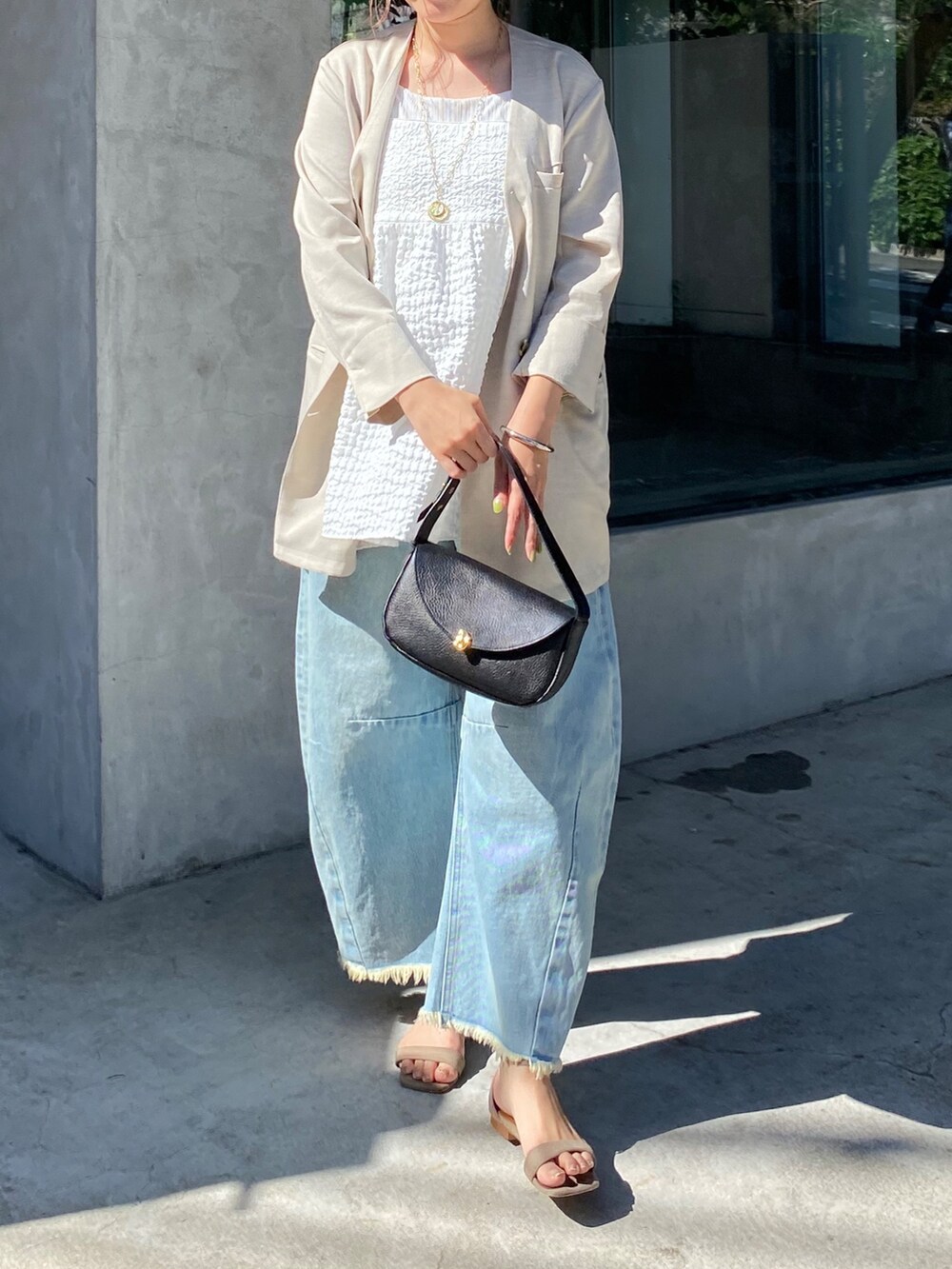 ホワイト系のキャミソール、ブルー系のデニムパンツ、ブラック系のショルダーバッグを着用したレディースの夏コーディネートの2枚目の写真