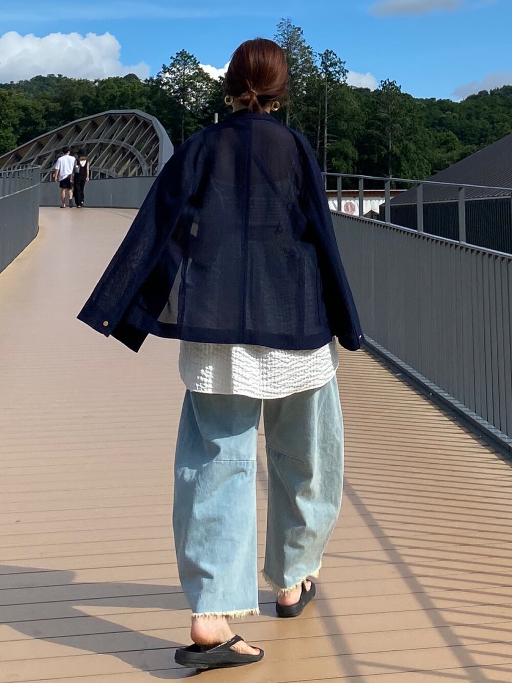 ブルー系のテーラードジャケット、ホワイト系のキャミソール、ブルー系のデニムパンツを着用したレディースの夏コーディネートの8枚目の写真