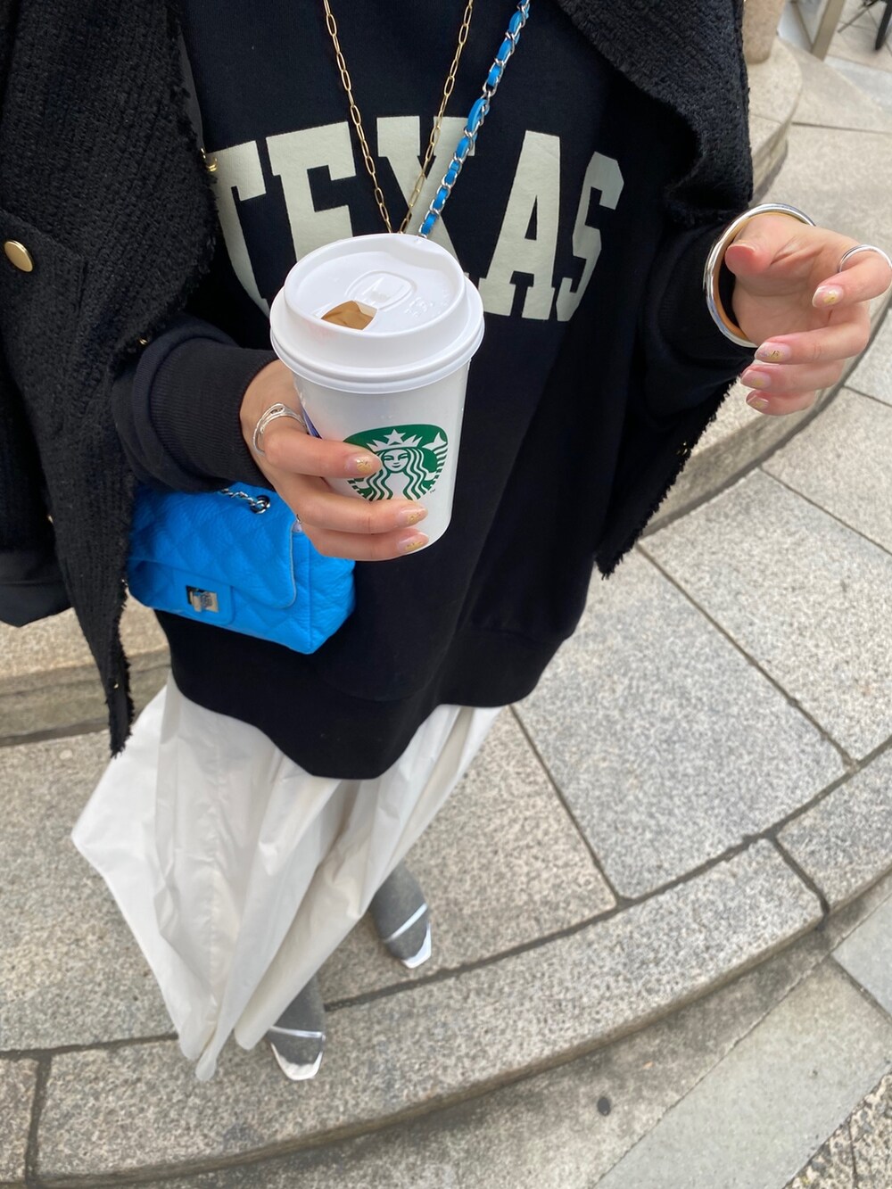 ブラック系のスウェット、ブラック系のノーカラージャケット、ホワイト系のスカートを着用したレディースの春コーディネートの5枚目の写真