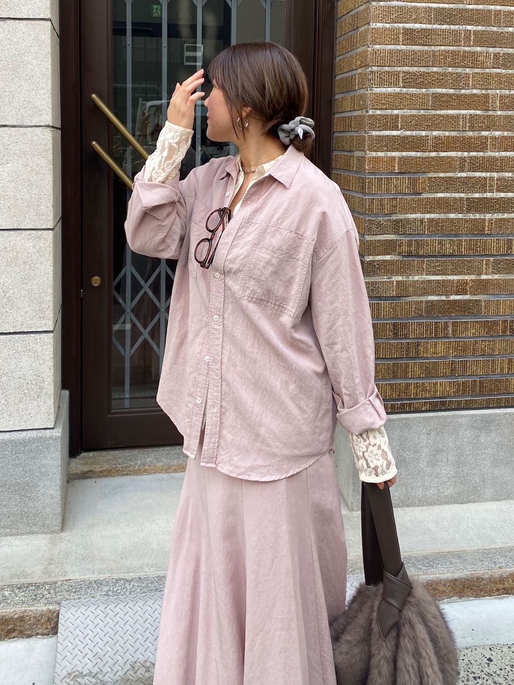 ピンク系のシャツ/ブラウス、ピンク系のスカート、ブラウン系のショルダーバッグを着用したレディースの冬コーディネートの2枚目の写真