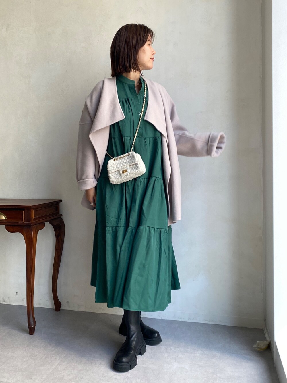 ベージュ系のその他アウター、グリーン系のワンピース、ブラック系のブーツを着用したレディースの秋コーディネートの3枚目の写真