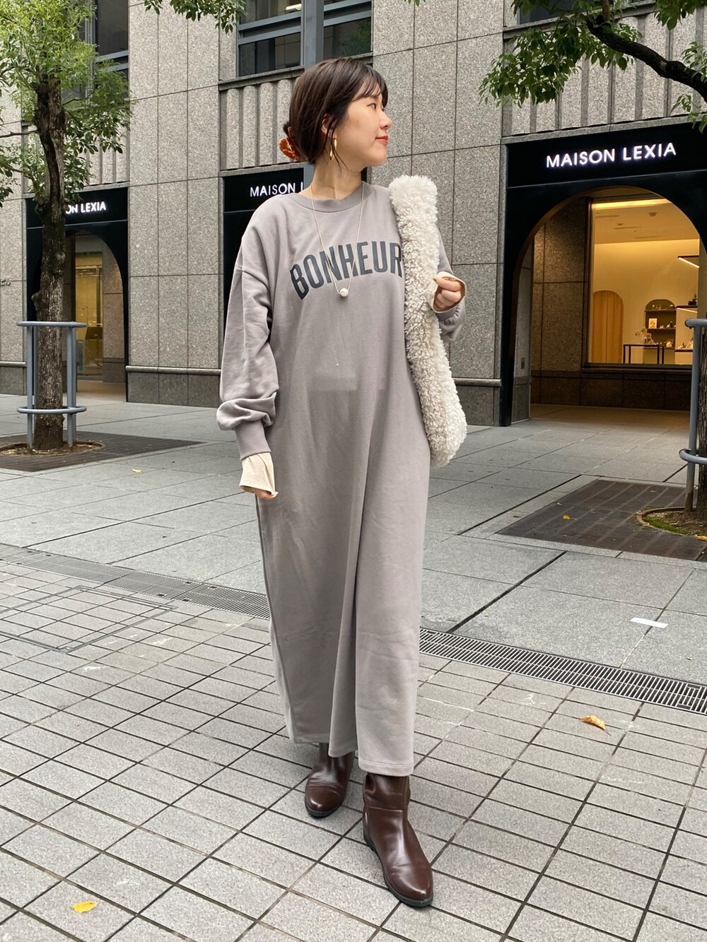 グレー系のワンピース、ブラウン系のブーツ、ゴールド系のTシャツ/カットソーを着用したレディースの秋コーディネートの7枚目の写真