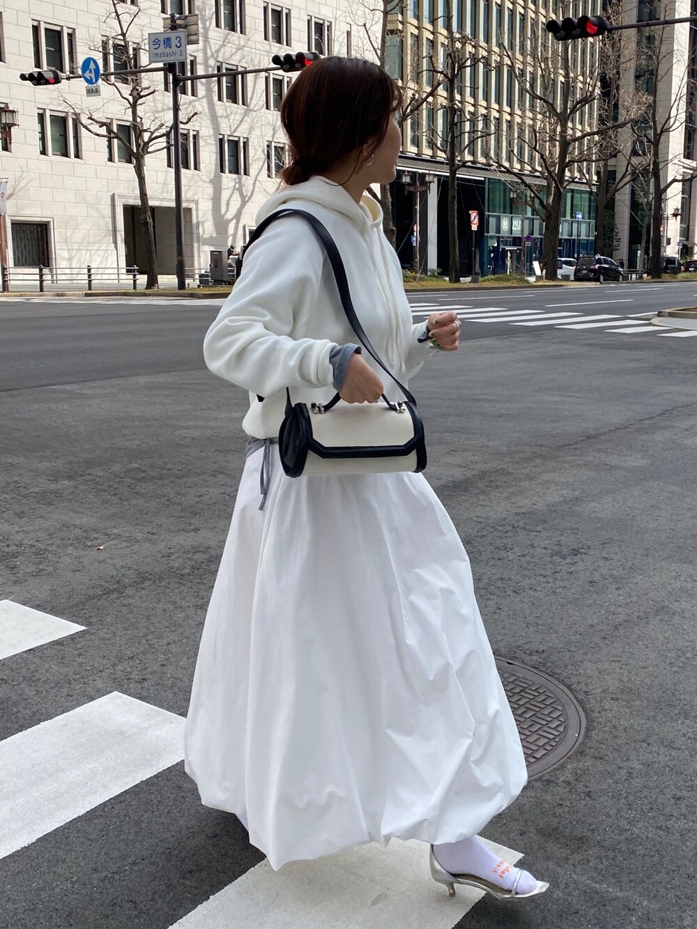 ホワイト系のスカート、ブラウン系のショルダーバッグ、グレー系のTシャツ/カットソーを着用したレディースの春コーディネートの3枚目の写真