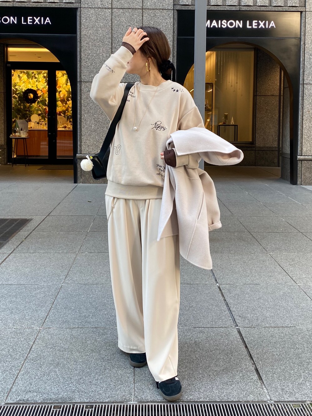 ホワイト系のその他アウター、ベージュ系のスラックス、ブラック系のショルダーバッグを着用したレディースの秋コーディネートの5枚目の写真