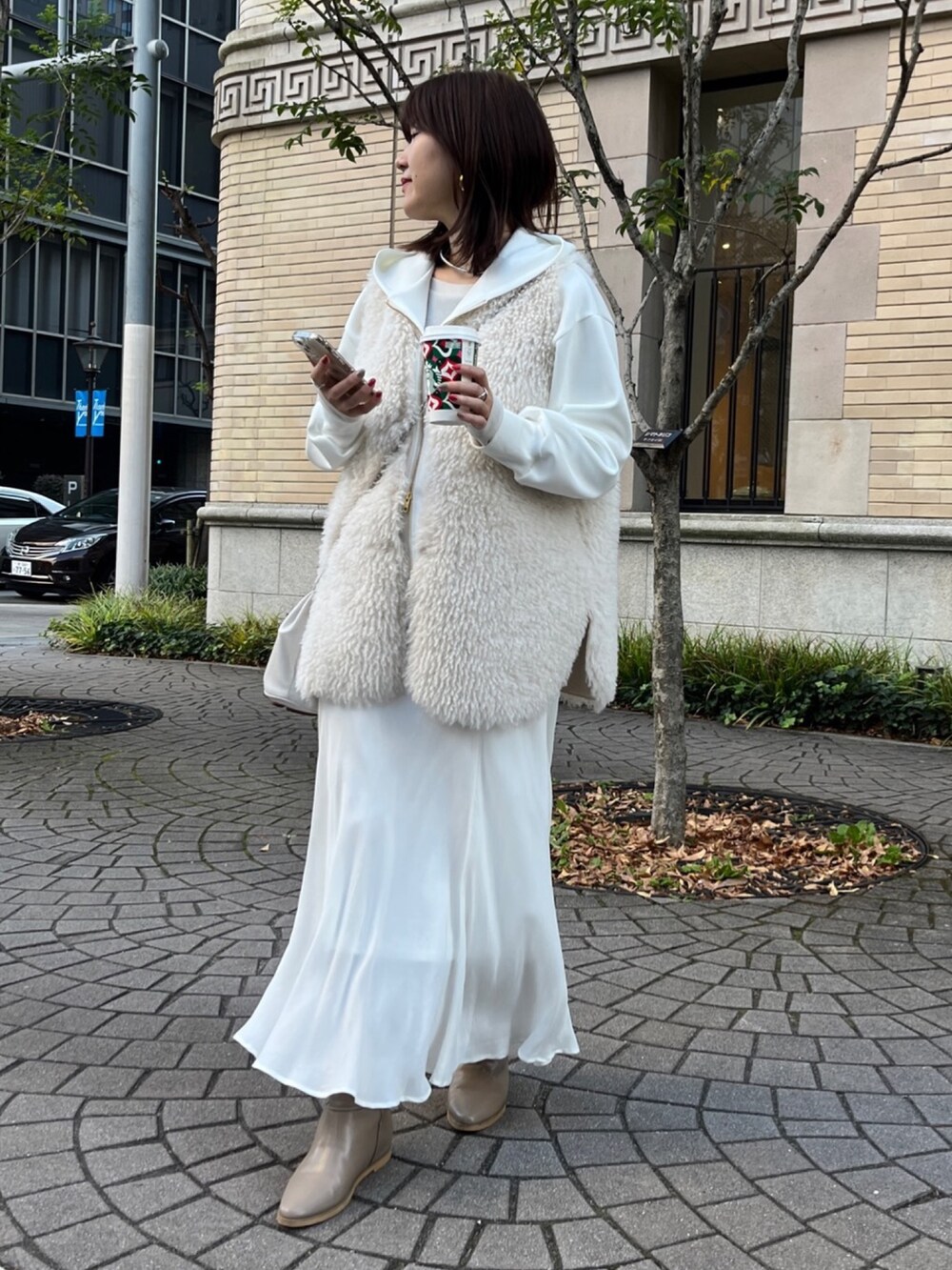 ホワイト系のベスト、ホワイト系のパーカー、ホワイト系のスカートを着用したレディースの冬コーディネートの8枚目の写真