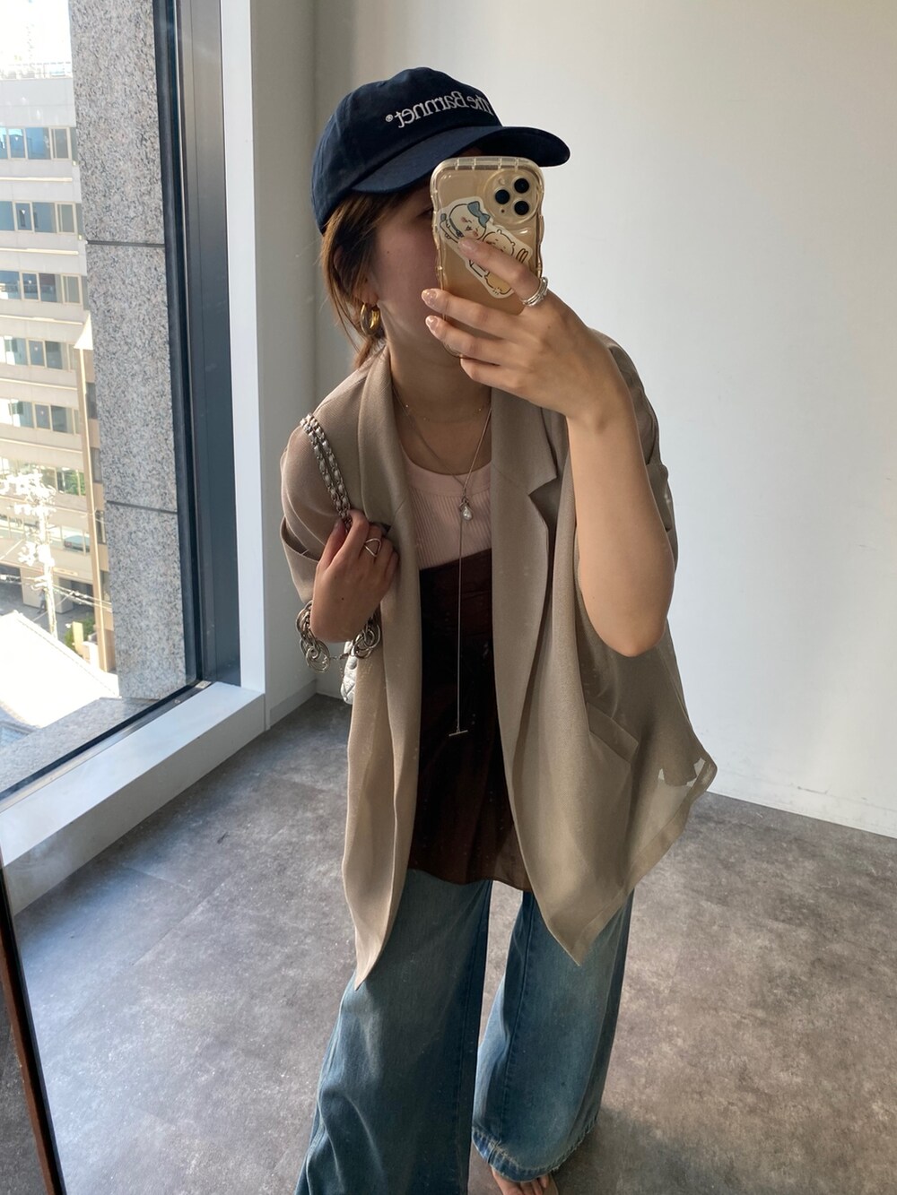 ベージュ系のテーラードジャケット、ブラウン系のキャミソール、ブルー系のデニムパンツを着用したレディースの夏コーディネートの9枚目の写真