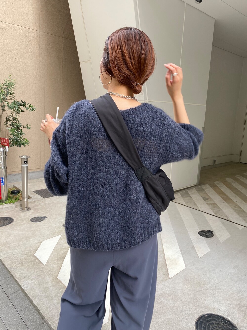 グレー系のニット/セーター、グレー系のスラックス、ブラック系のショルダーバッグを着用したレディースの秋コーディネートの6枚目の写真