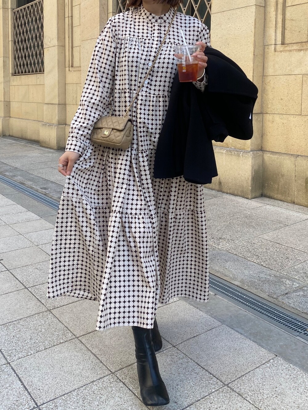 ベージュ系のワンピース、ブラック系のその他シューズ、ベージュ系のショルダーバッグを着用したレディースの冬コーディネートの2枚目の写真