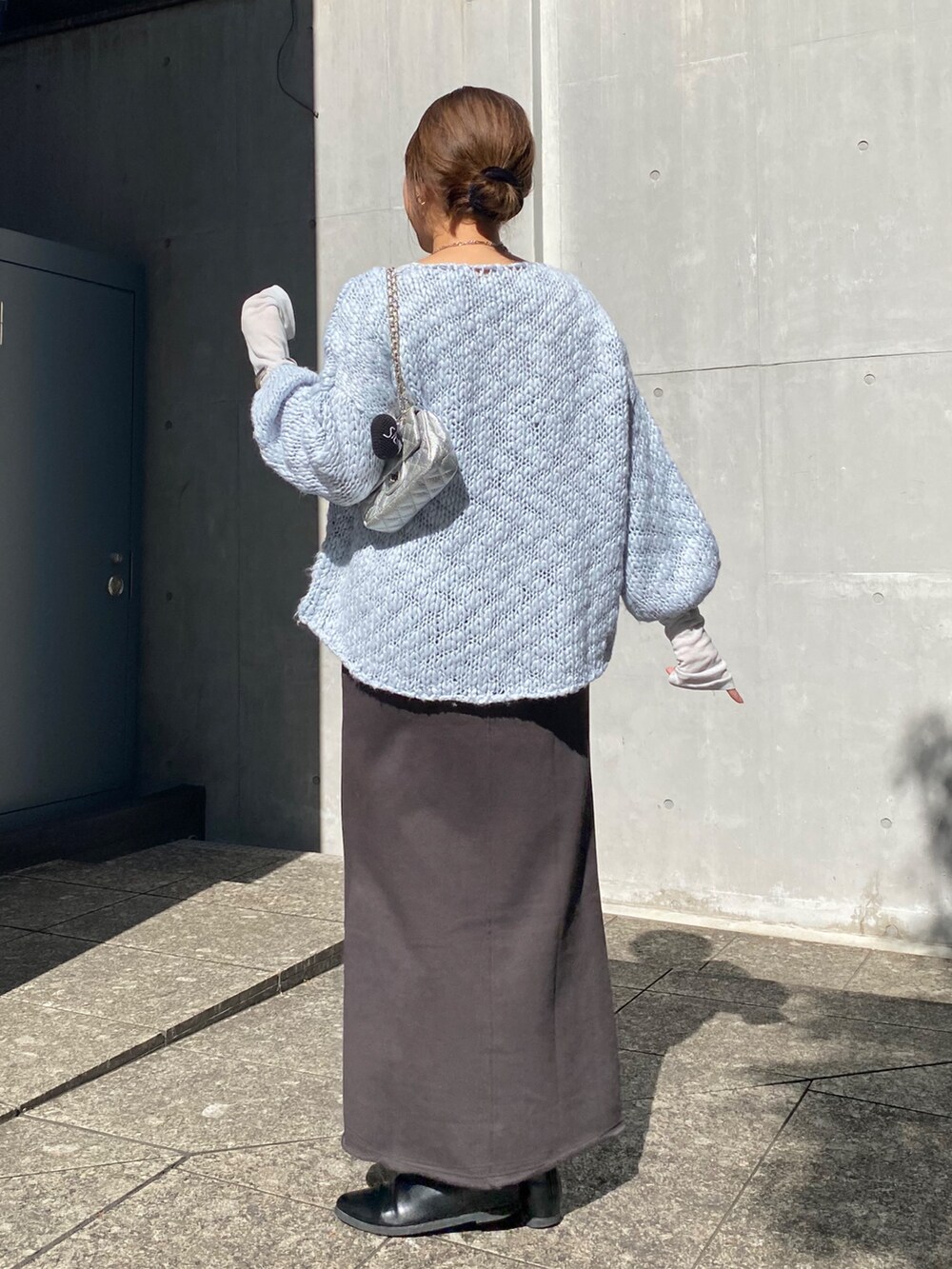 ブルー系のニット/セーター、ブルー系のTシャツ/カットソー、グレー系のムートンコートを着用したレディースの冬コーディネートの3枚目の写真