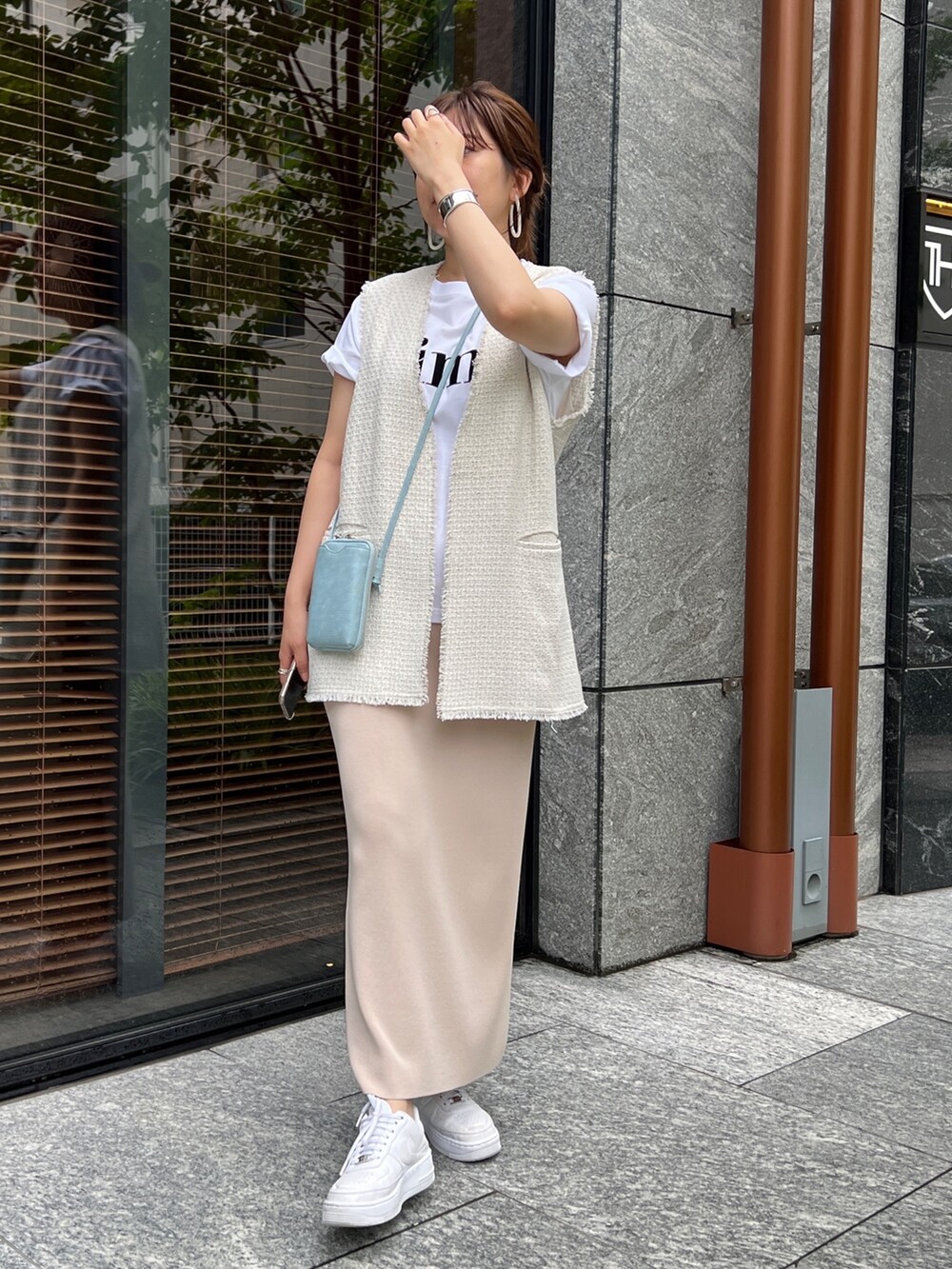 ホワイト系のベスト、ベージュ系のスカートを着用したレディースの夏コーディネートの2枚目の写真