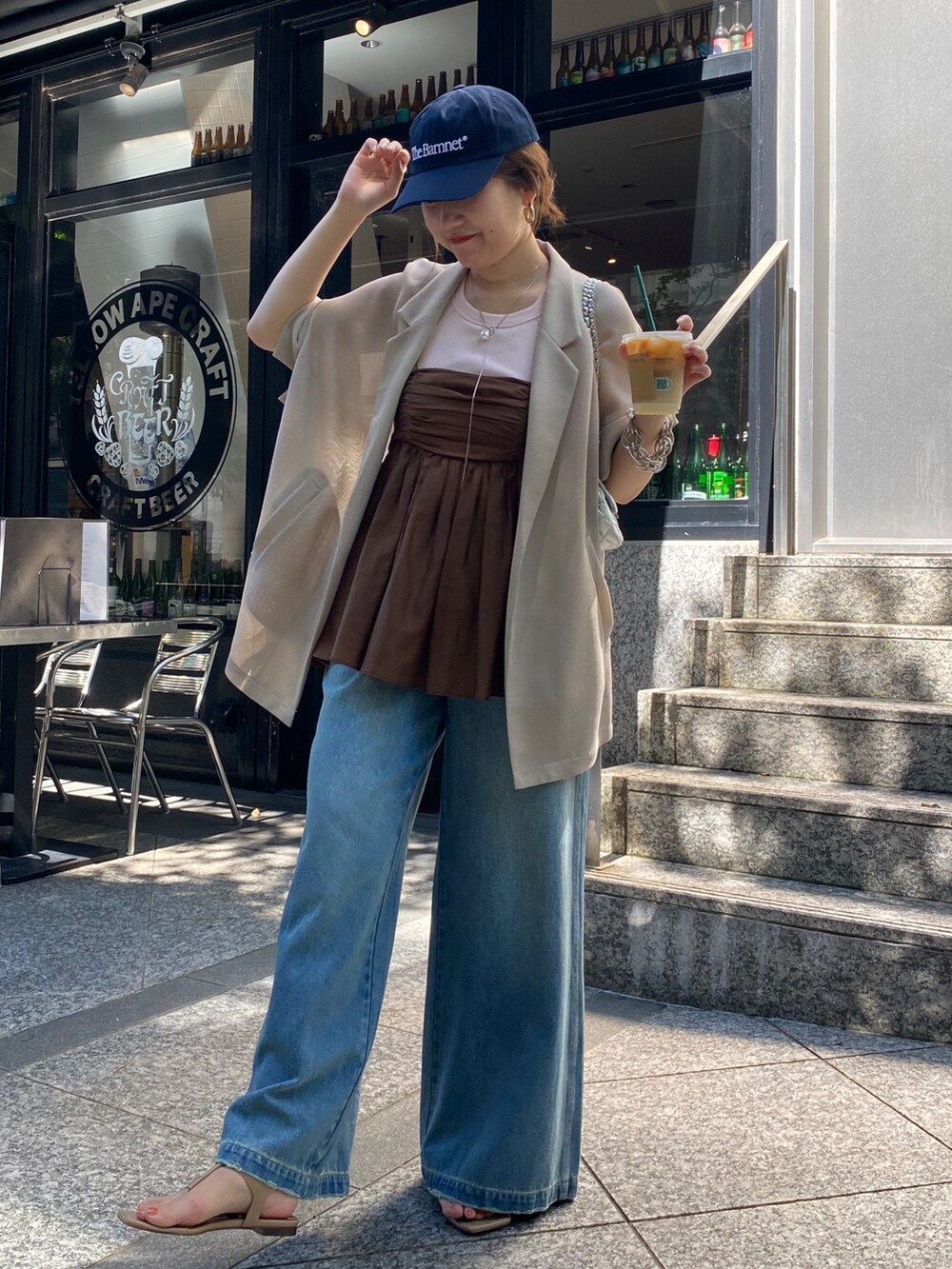 ベージュ系のテーラードジャケット、ブラウン系のキャミソール、ブルー系のデニムパンツを着用したレディースの夏コーディネートの4枚目の写真
