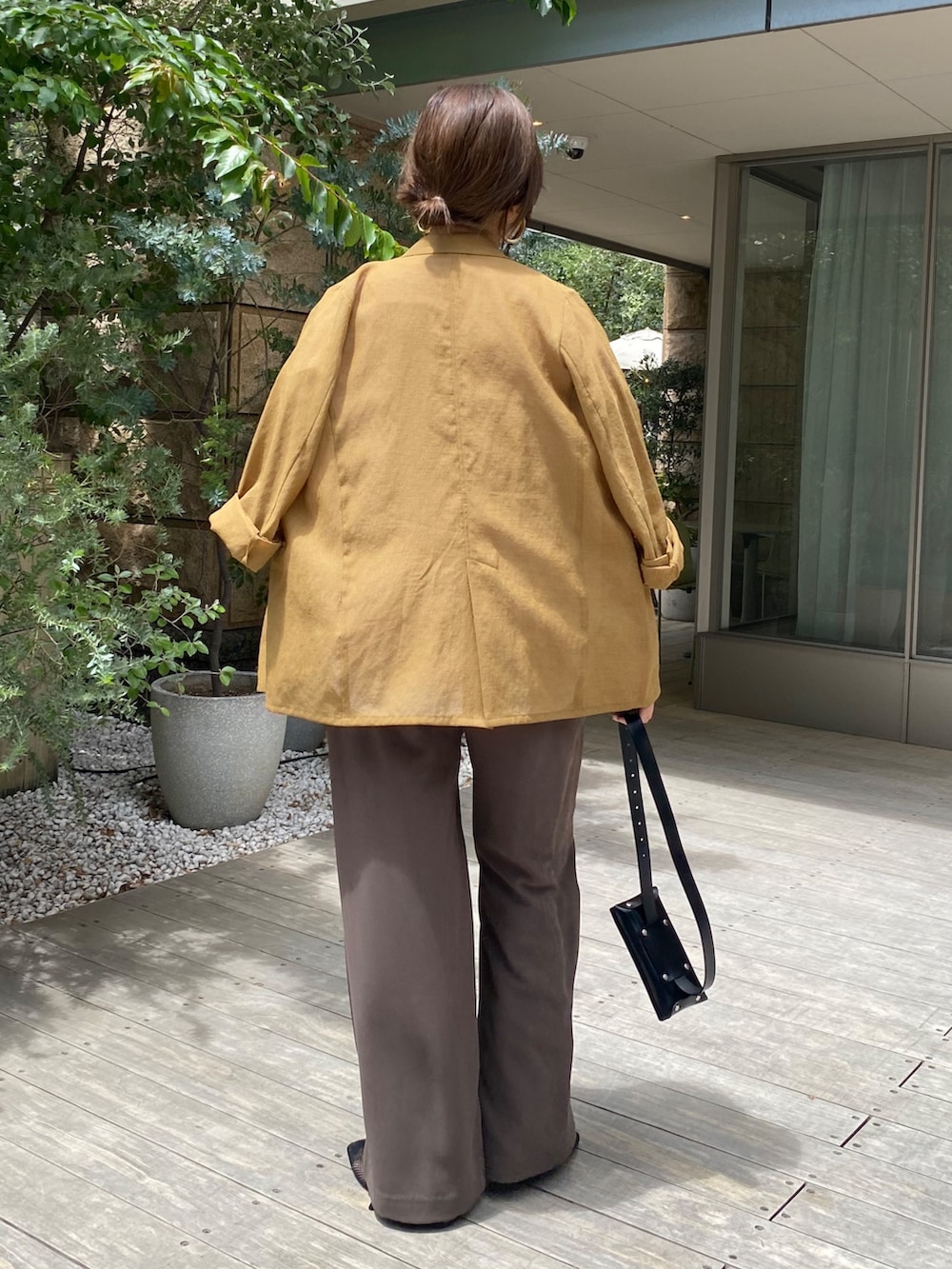 イエロー系のテーラードジャケット、ホワイト系のTシャツ/カットソー、ブラウン系のスラックスを着用したレディースの夏コーディネートの8枚目の写真