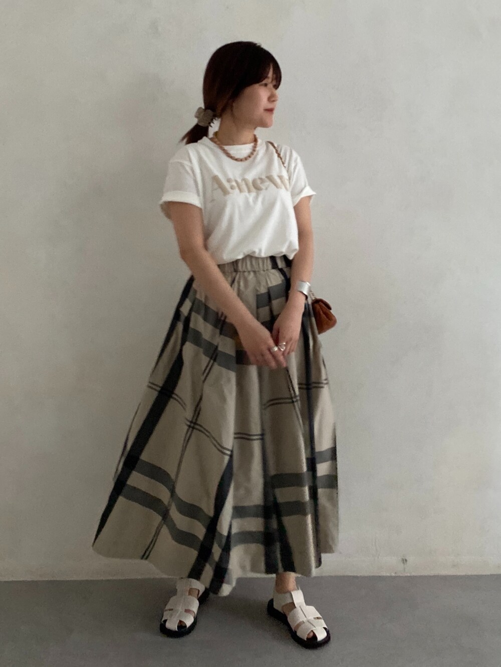 ブラック系のサンダル、ホワイト系のTシャツ/カットソー、ベージュ系のスカートを着用したレディースの夏コーディネートの5枚目の写真