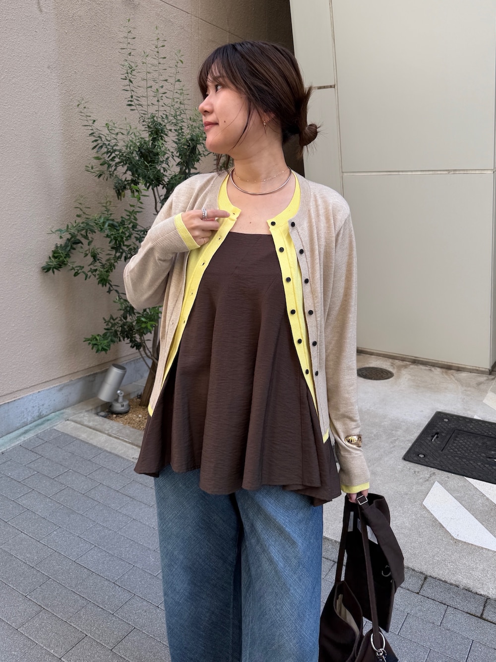 ベージュ系のカーディガン/ボレロ、ブラウン系のキャミソール、ブルー系のデニムパンツを着用したレディースの秋コーディネートの5枚目の写真