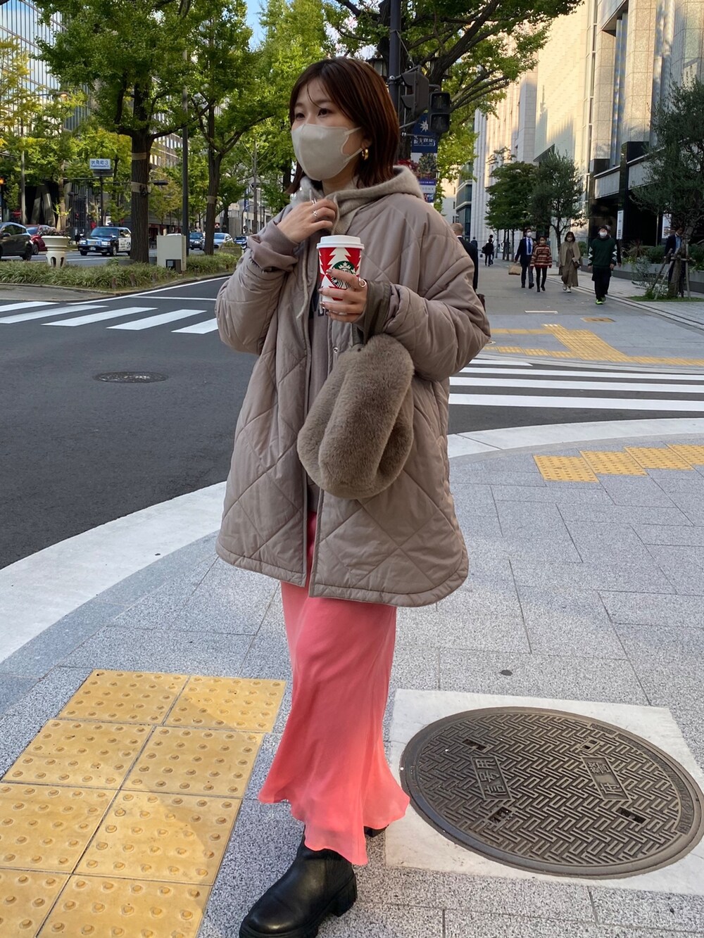 ベージュ系のノーカラーコート、ピンク系のスカート、ブラック系のブーツを着用したレディースの秋コーディネートの2枚目の写真