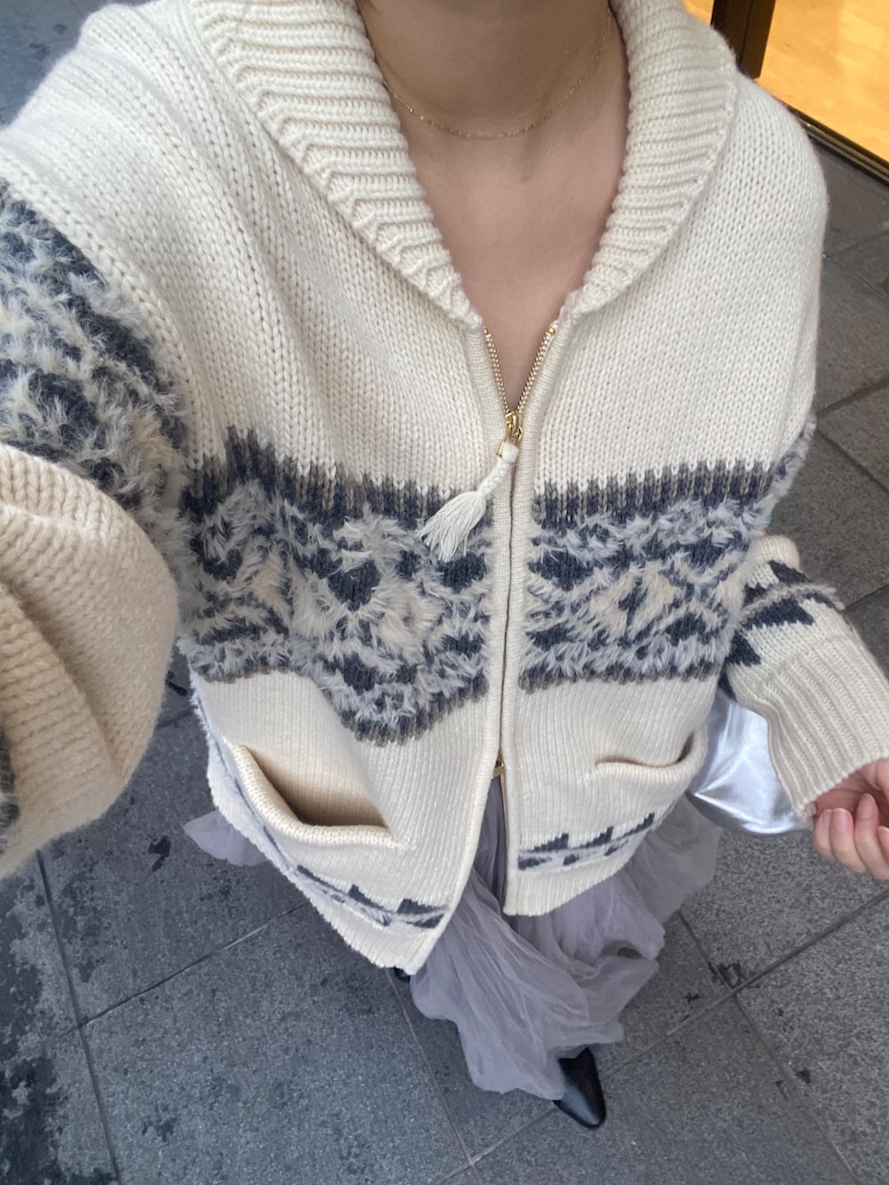 ホワイト系のニット/セーター、グレー系のスカート、シルバー系のショルダーバッグを着用したレディースの冬コーディネートの4枚目の写真