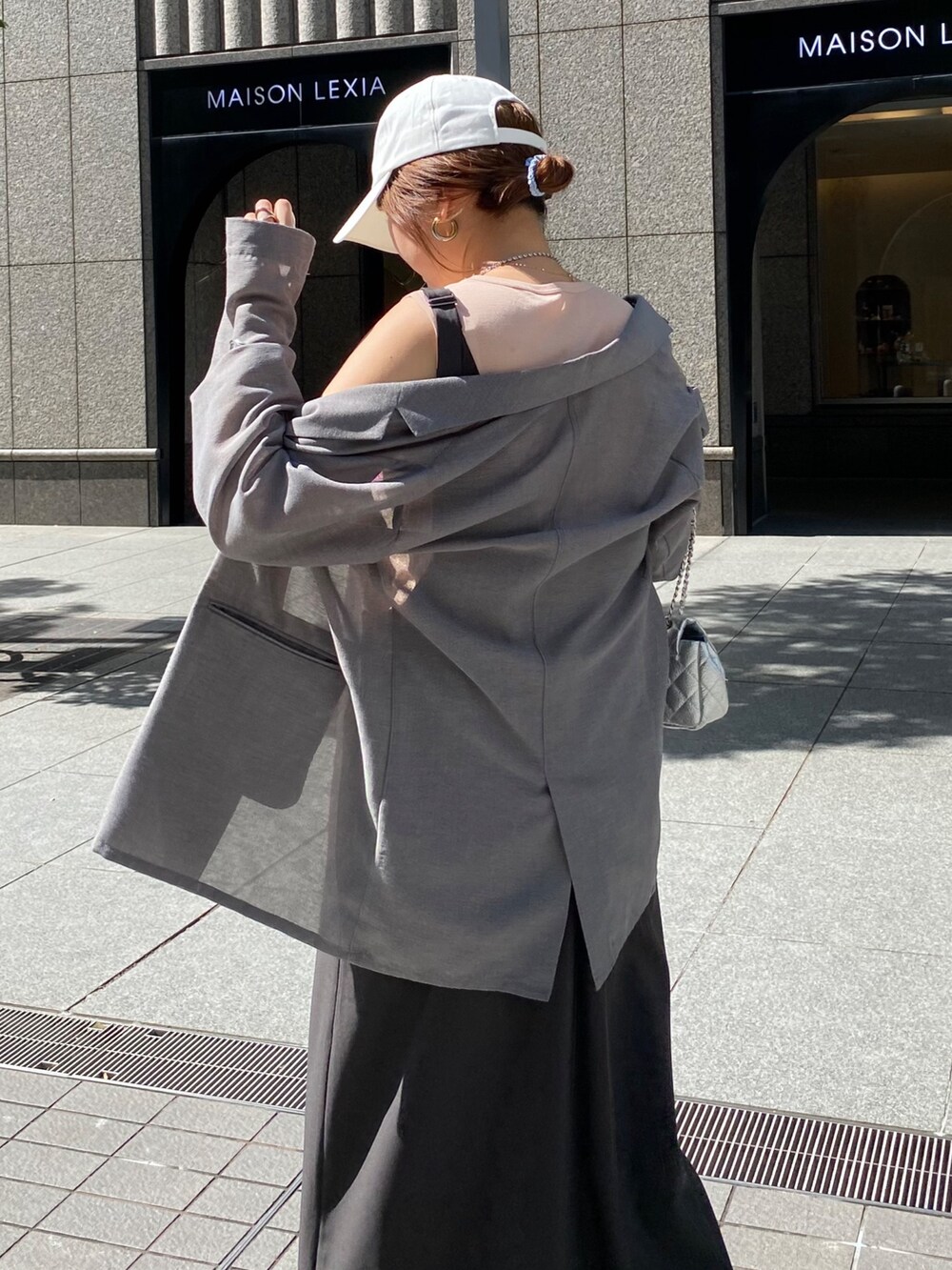 グレー系のワンピース、グレー系のテーラードジャケット、シルバー系のネックレスを着用したレディースの秋コーディネートの5枚目の写真