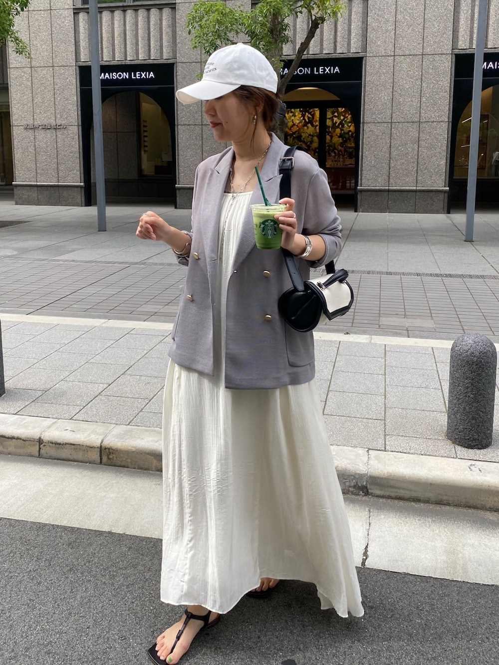 ブルー系のテーラードジャケット、ホワイト系のワンピース、ブラウン系のショルダーバッグを着用したレディースの春コーディネートの5枚目の写真