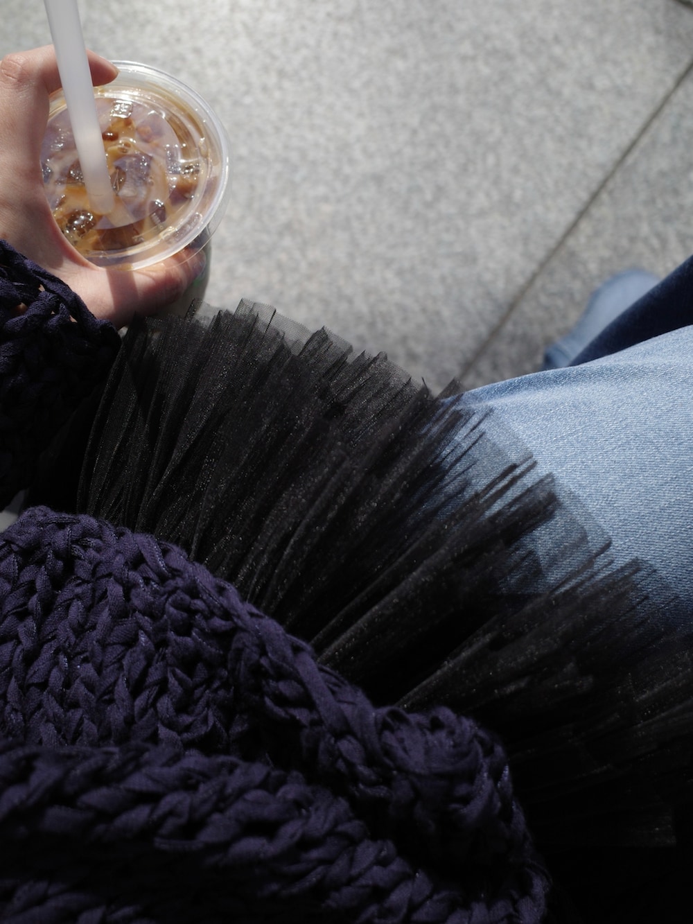 ブルー系のニット/セーター、ブラック系のシャツ/ブラウス、ブルー系のデニムパンツを着用したレディースの春コーディネートの3枚目の写真