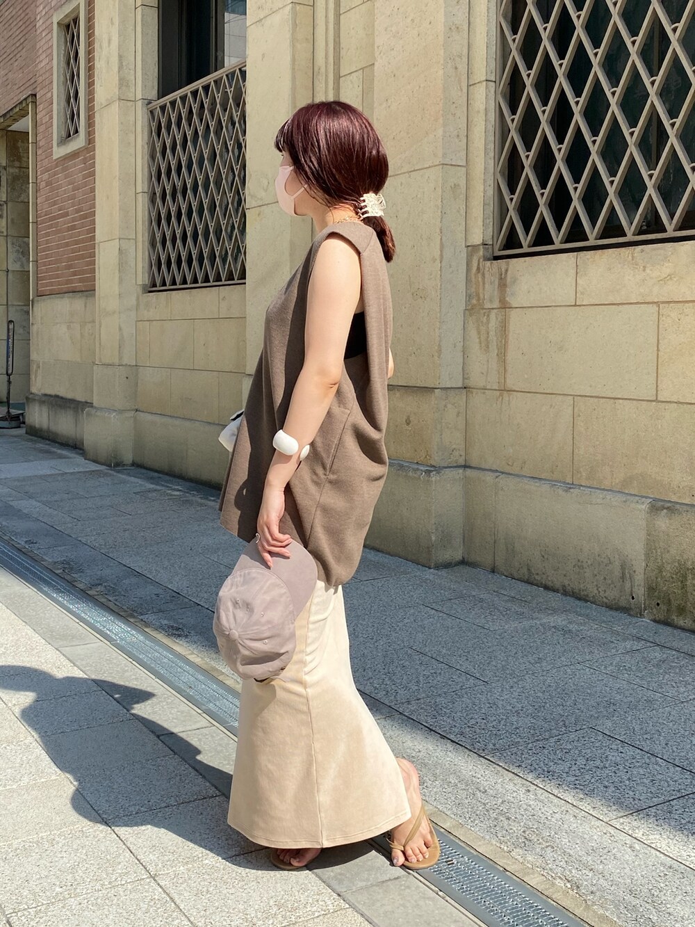ブラウン系のベスト、ホワイト系のスカート、ホワイト系のショルダーバッグを着用したレディースの夏コーディネートの4枚目の写真