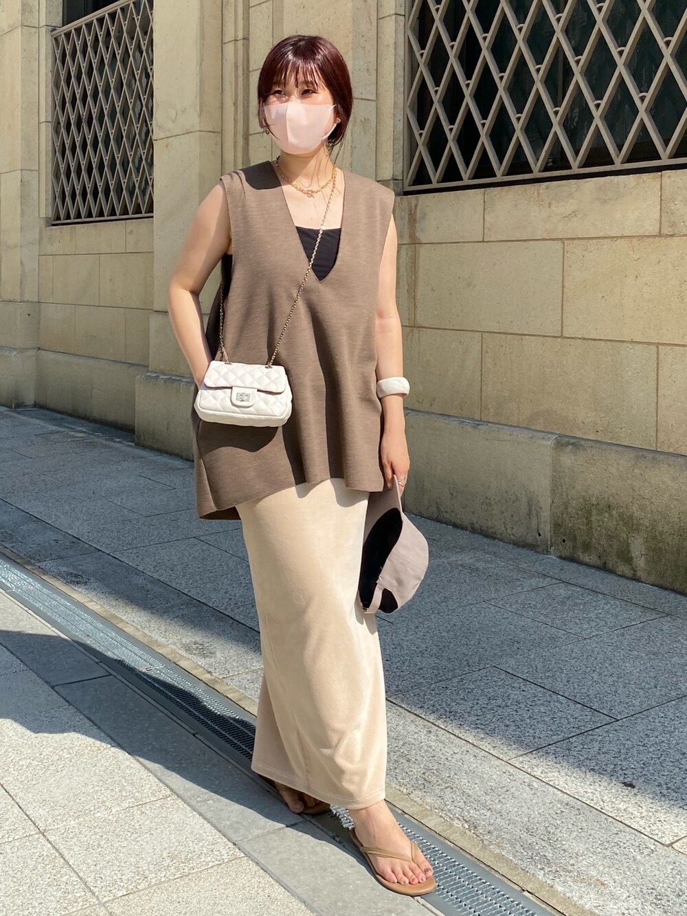ブラウン系のベスト、ホワイト系のスカート、ホワイト系のショルダーバッグを着用したレディースの夏コーディネートの3枚目の写真