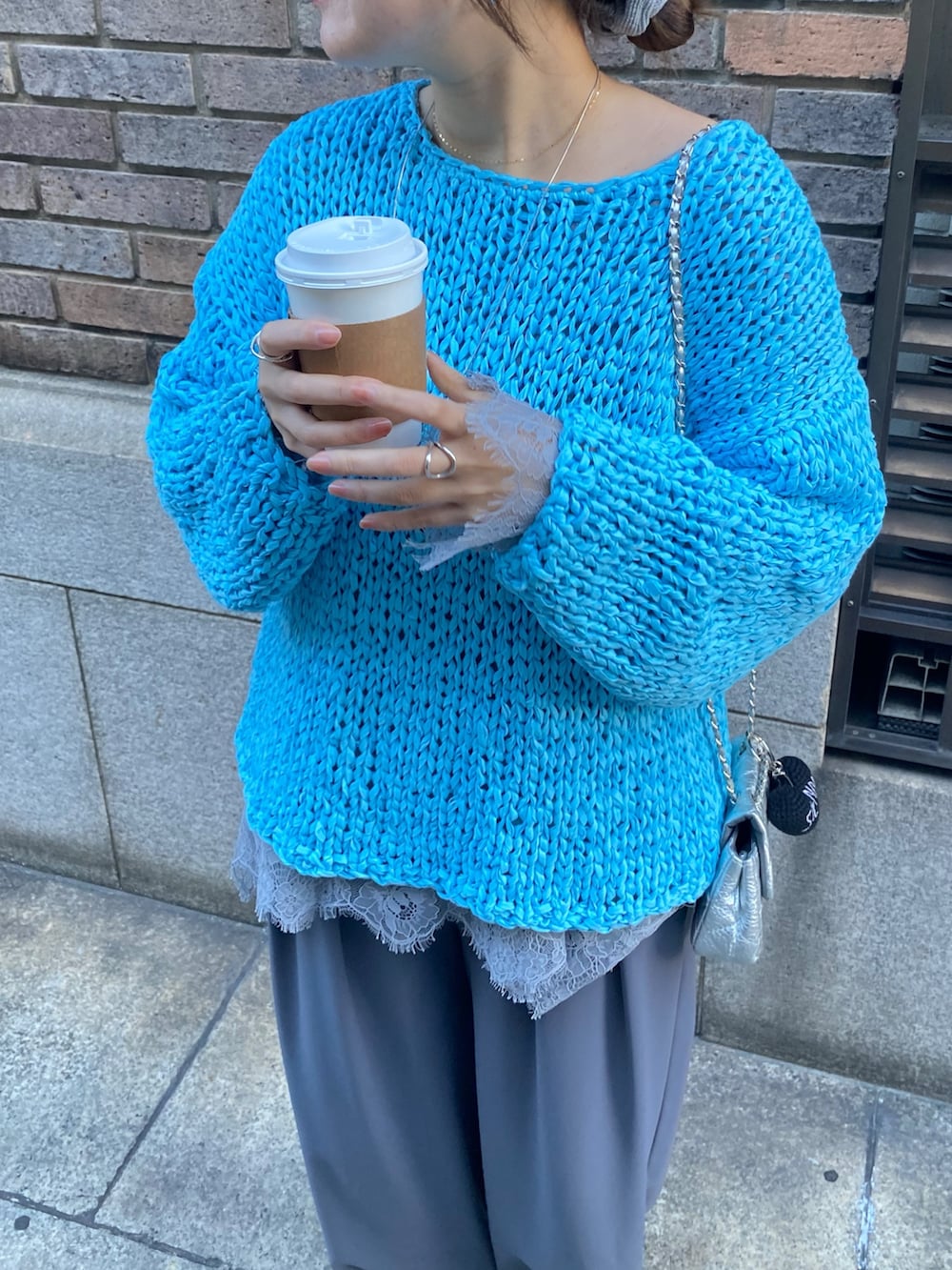 ブルー系のニット/セーター、グレー系のTシャツ/カットソー、グレー系のスラックスを着用したレディースの冬コーディネートの6枚目の写真