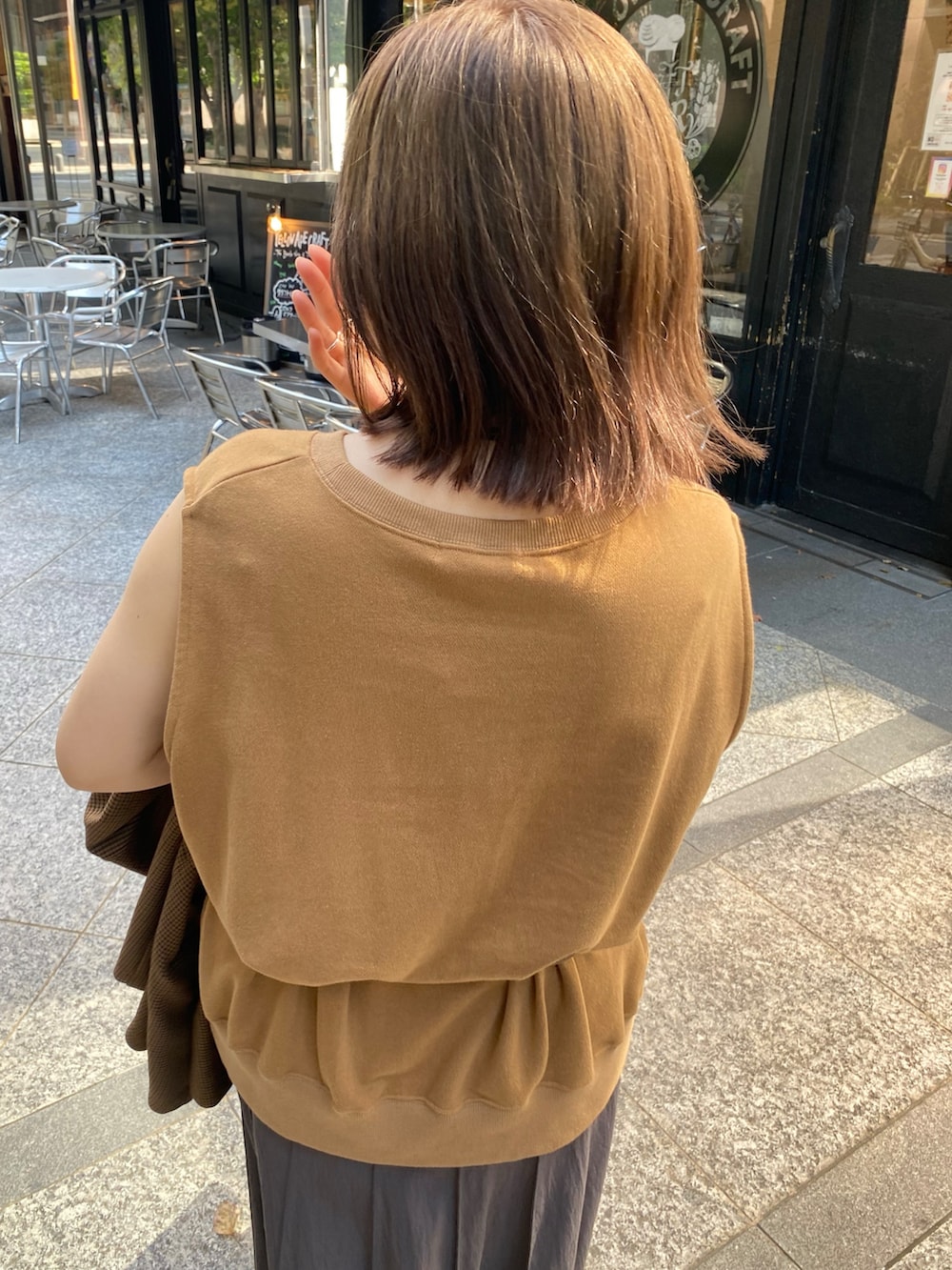 イエロー系のスウェット、グレー系のスカート、ブラウン系のテーラードジャケットを着用したレディースの夏コーディネートの9枚目の写真