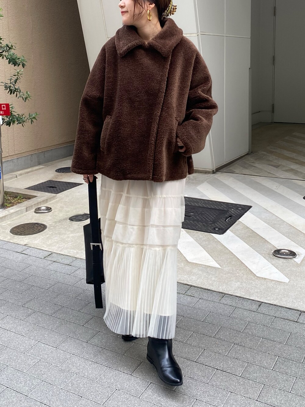 ブラウン系のその他アウター、オレンジ系のスウェット、ホワイト系のスカートを着用したレディースの冬コーディネートの6枚目の写真