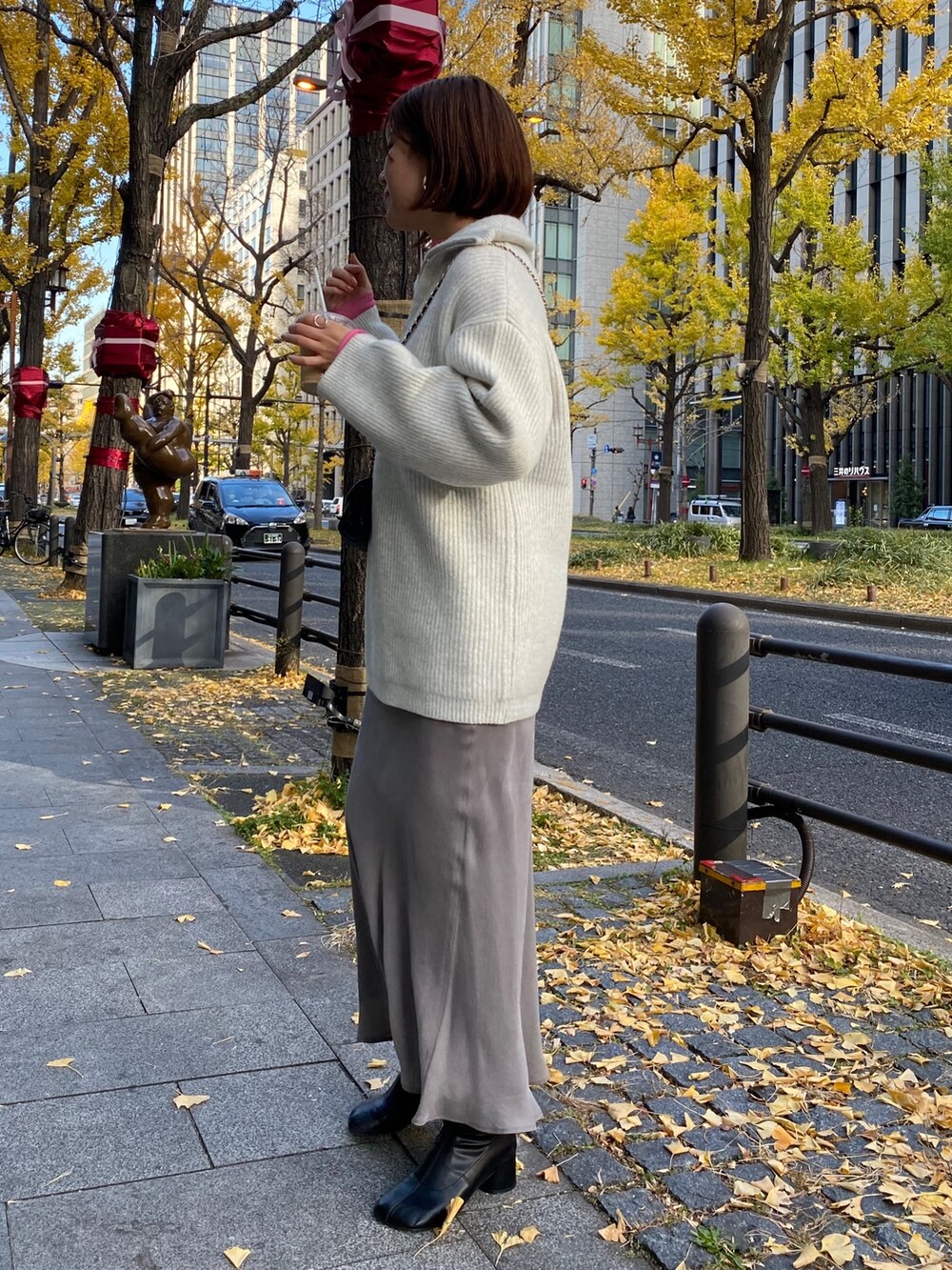 ピンク系のTシャツ/カットソー、グレー系のニット/セーター、グレー系のスカートを着用したレディースの冬コーディネートの6枚目の写真