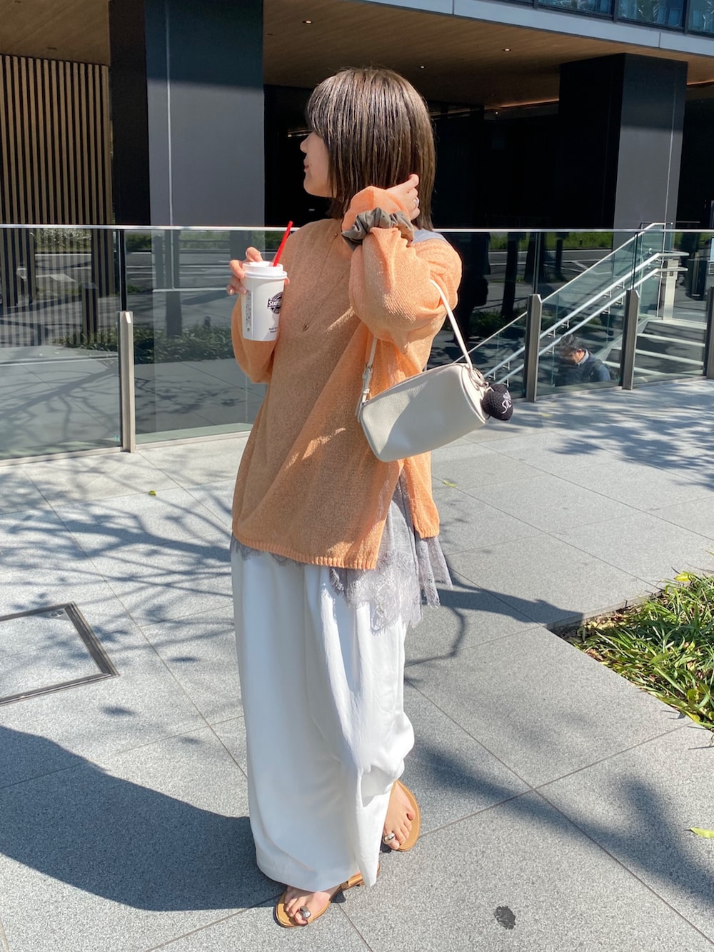 オレンジ系のニット/セーター、グレー系のTシャツ/カットソー、ホワイト系のその他パンツを着用したレディースの春コーディネートの3枚目の写真