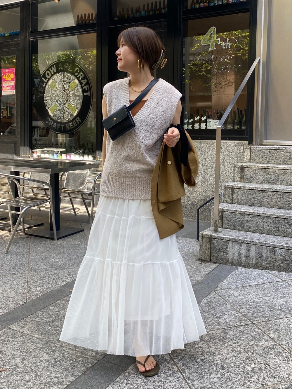 イエロー系のテーラードジャケット、ベージュ系のニット/セーター、ブラウン系のタンクトップを着用したレディースの夏コーディネートの2枚目の写真