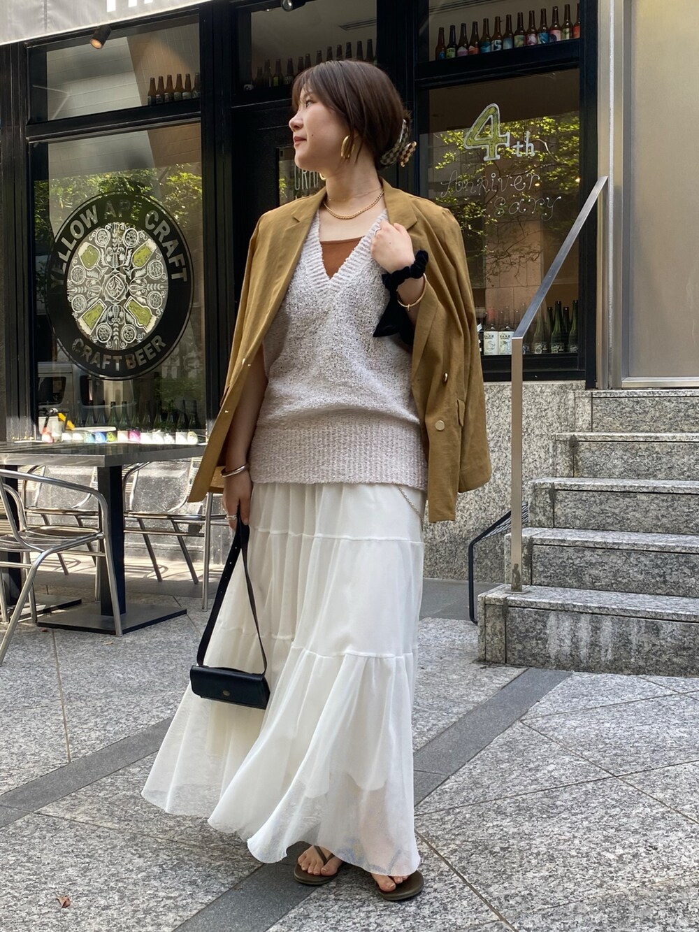 イエロー系のテーラードジャケット、ベージュ系のニット/セーター、ブラウン系のタンクトップを着用したレディースの夏コーディネートの4枚目の写真