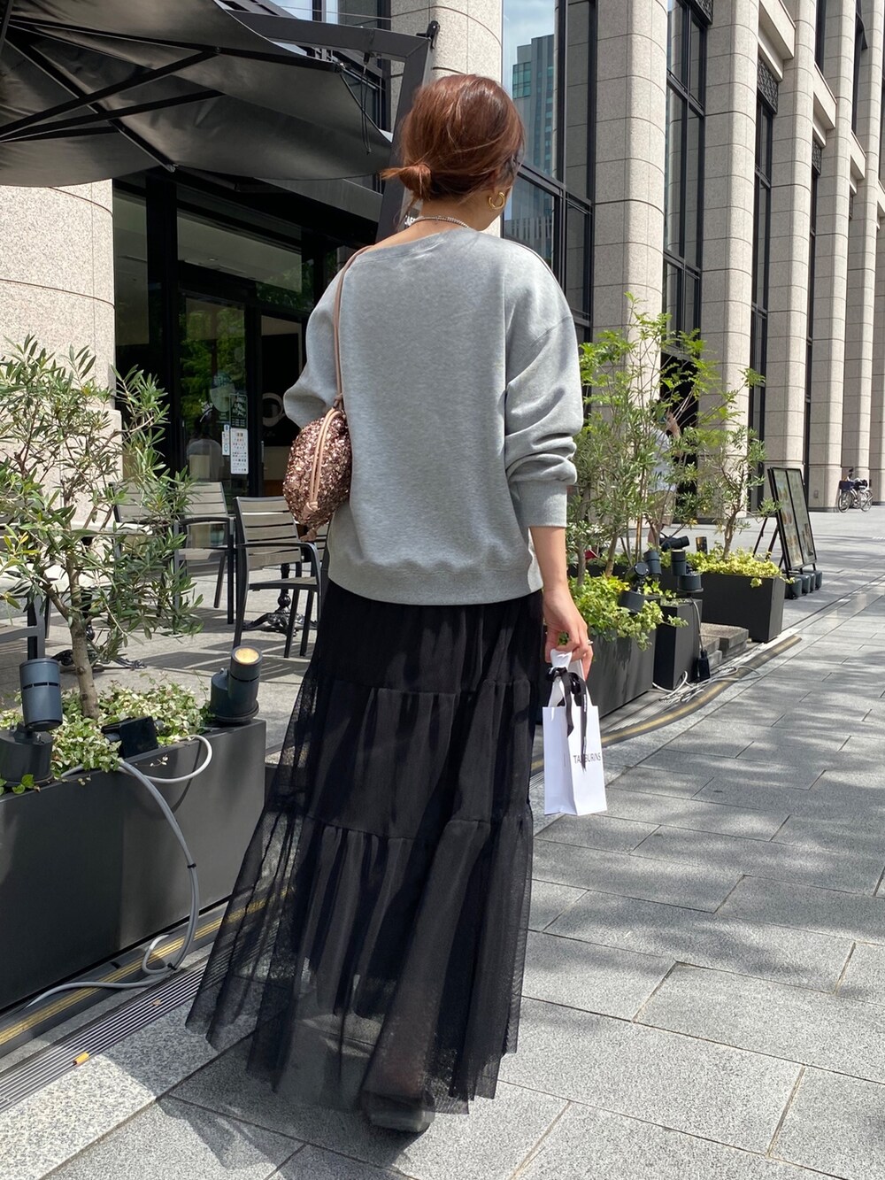 グレー系のスウェット、ブラック系のスカート、ピンク系のハンドバッグを着用したレディースの秋コーディネートの2枚目の写真