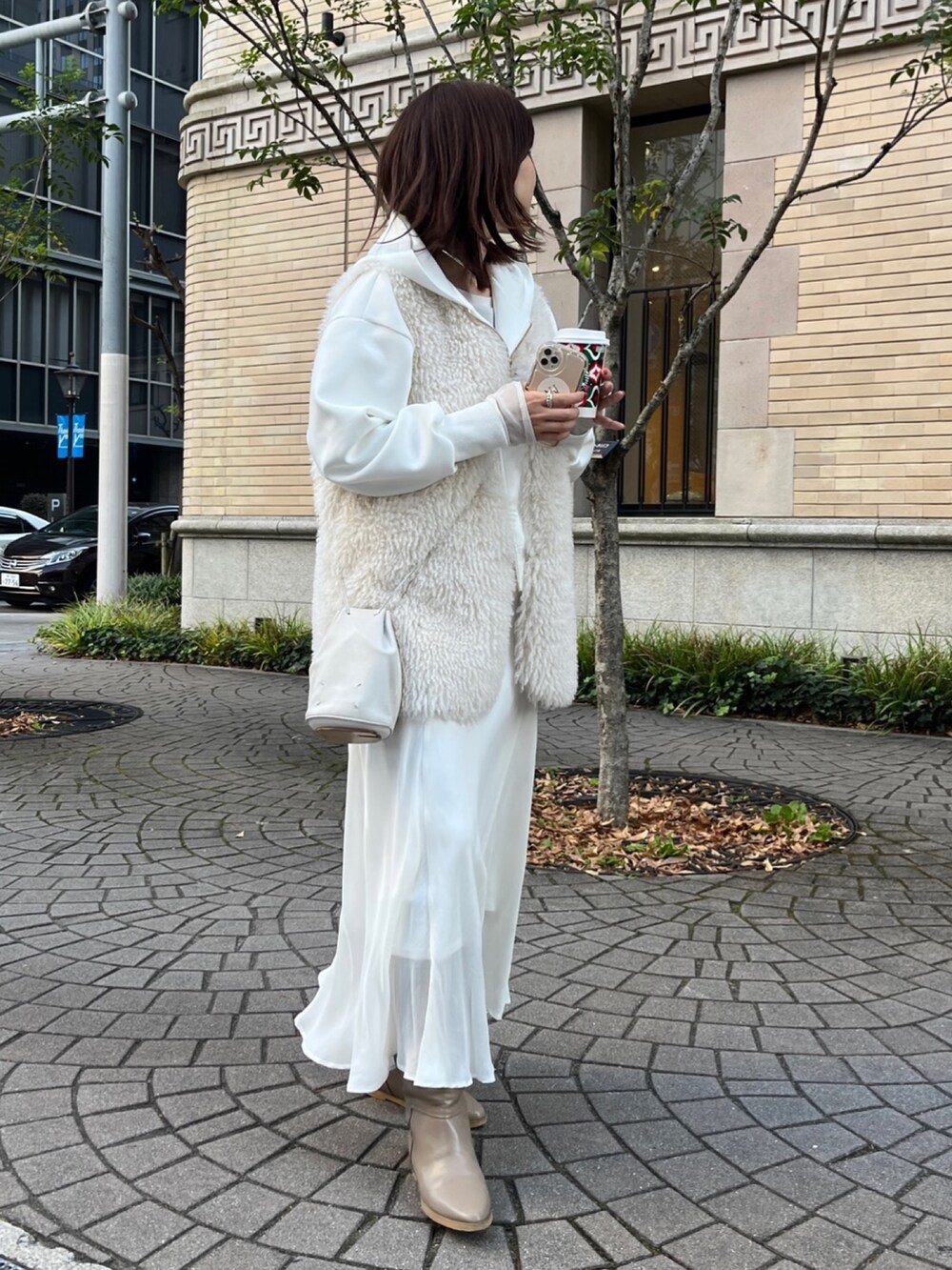 ホワイト系のベスト、ホワイト系のパーカー、ホワイト系のスカートを着用したレディースの冬コーディネートの7枚目の写真