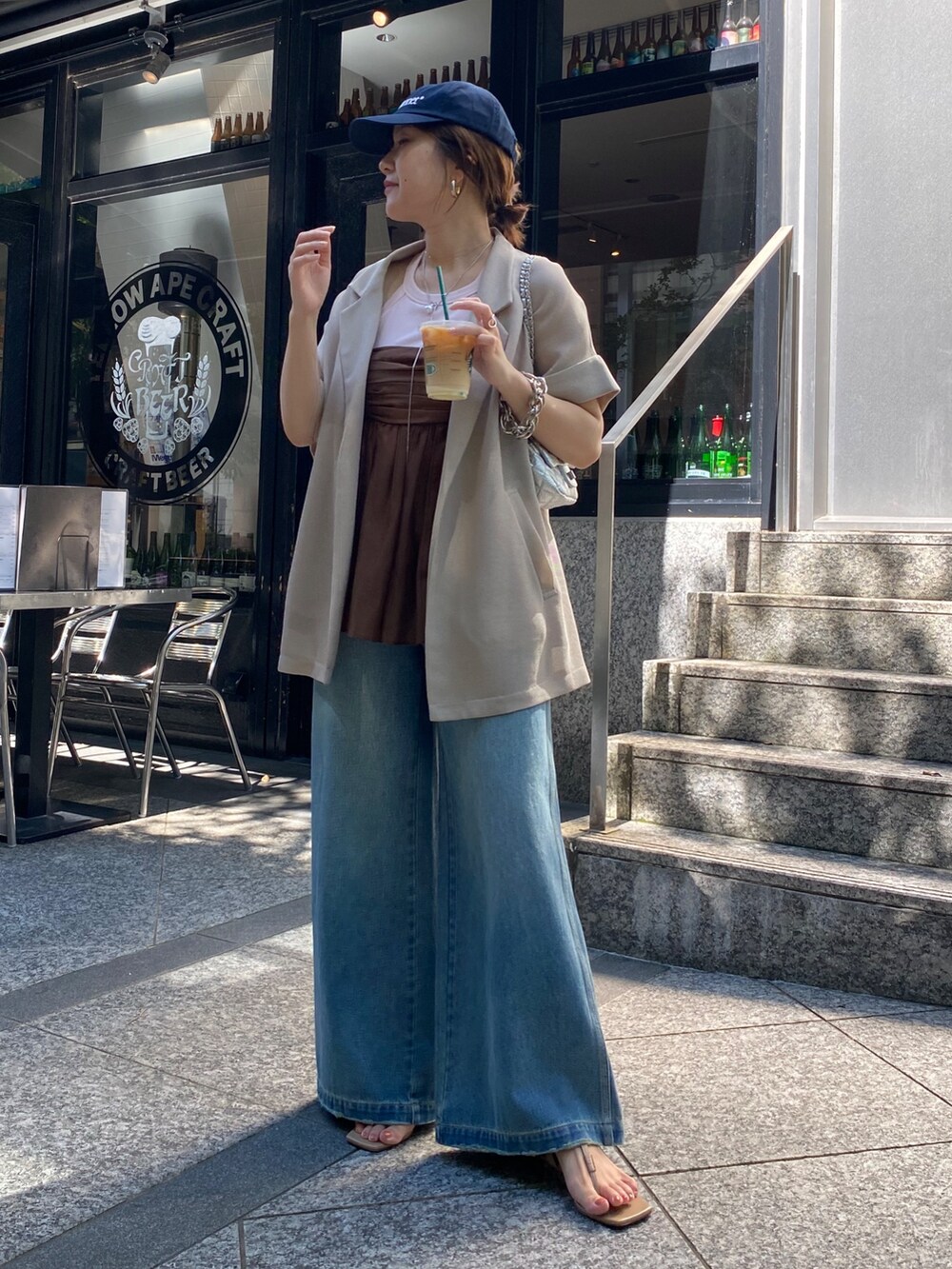 ベージュ系のテーラードジャケット、ブラウン系のキャミソール、ブルー系のデニムパンツを着用したレディースの夏コーディネートの5枚目の写真