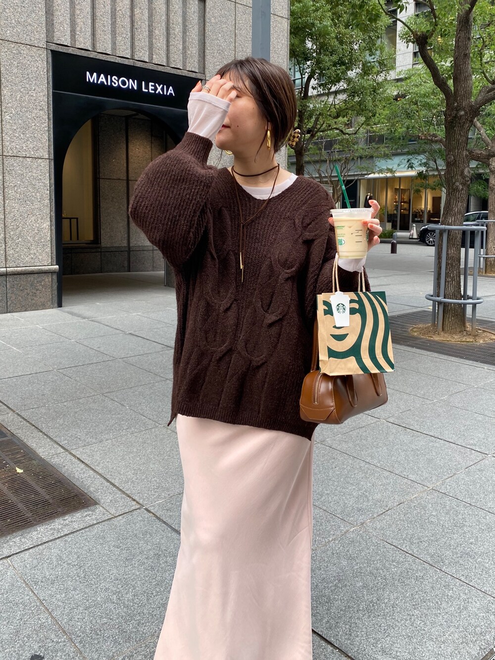 ブラウン系のニット/セーター、ピンク系のスカート、ブラック系のブーツを着用したレディースの冬コーディネートの9枚目の写真