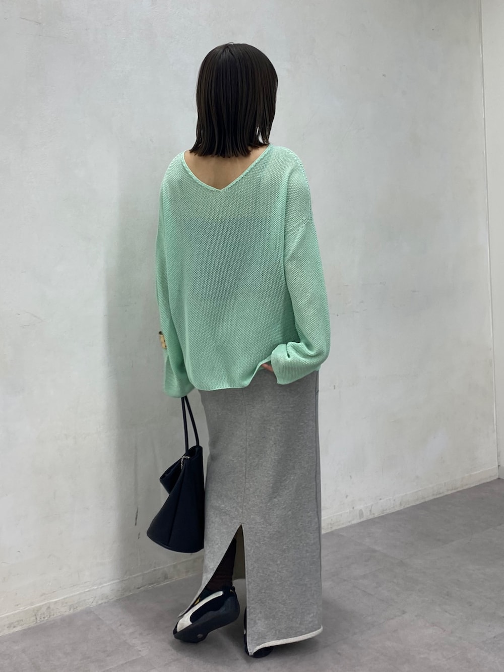 グリーン系のニット/セーター、グレー系のスカートを着用したレディースの春コーディネートの2枚目の写真
