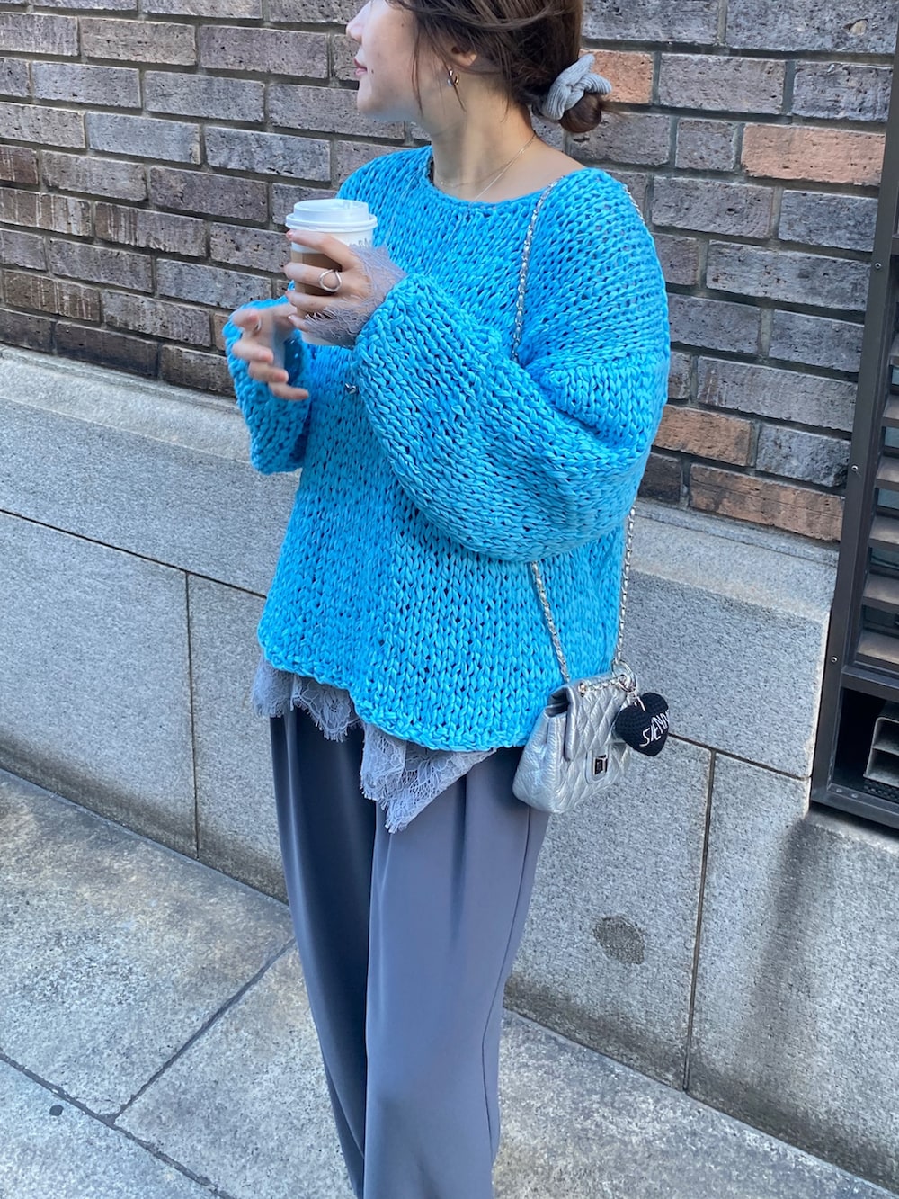 ブルー系のニット/セーター、グレー系のTシャツ/カットソー、グレー系のスラックスを着用したレディースの冬コーディネートの2枚目の写真