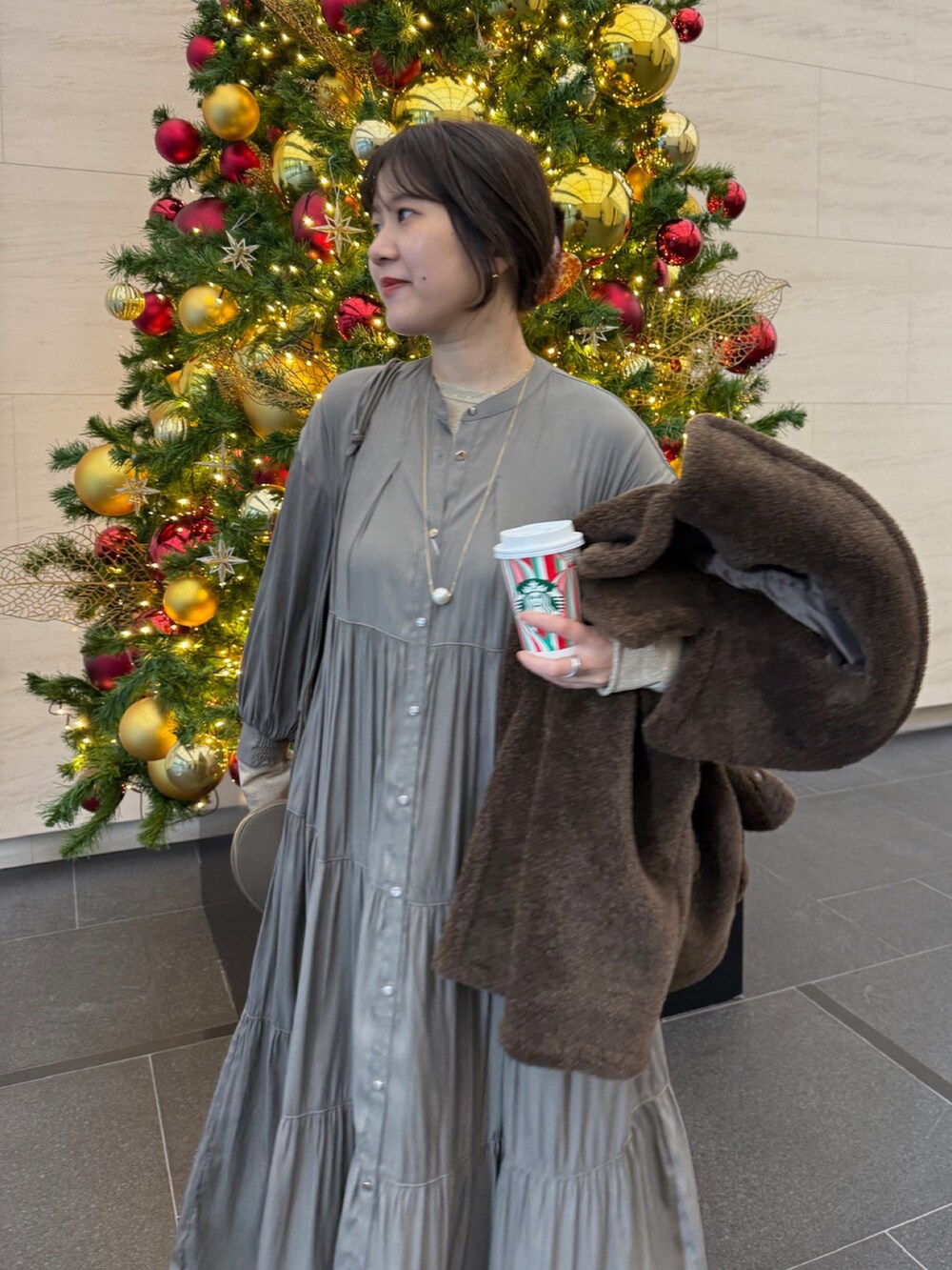 ブラウン系のその他アウター、ブラウン系のワンピース、ゴールド系のTシャツ/カットソーを着用したレディースの冬コーディネートの6枚目の写真