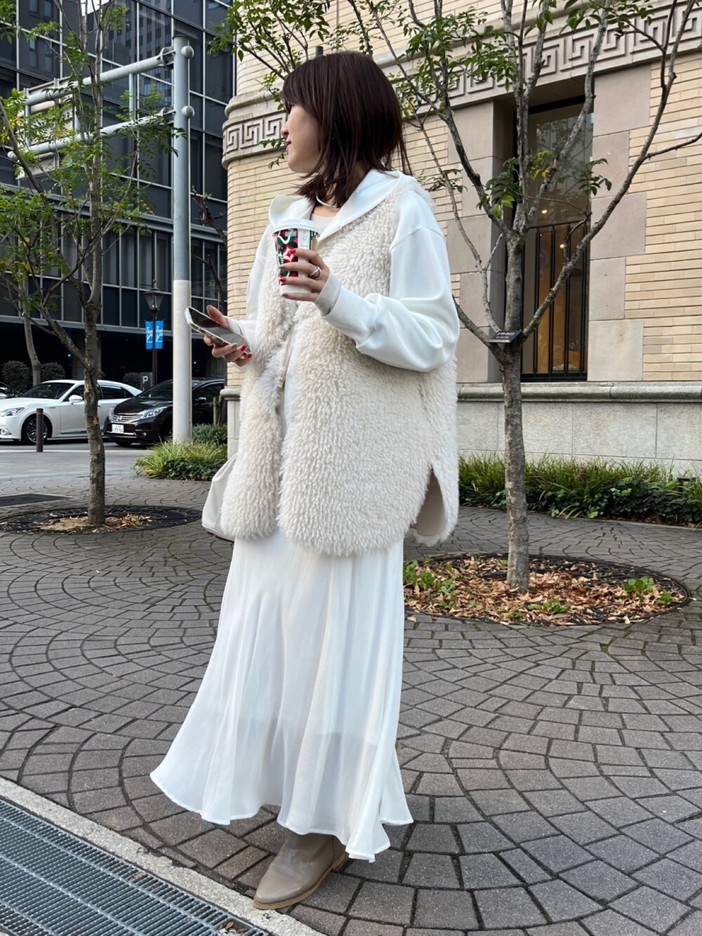 ホワイト系のベスト、ホワイト系のパーカー、ホワイト系のスカートを着用したレディースの冬コーディネートの2枚目の写真