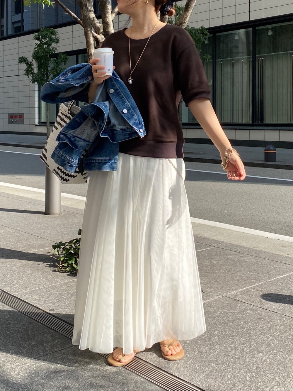 ブラウン系のスウェット、ホワイト系のスカート、ブルー系のデニムジャケットを着用したレディースの春コーディネートの9枚目の写真