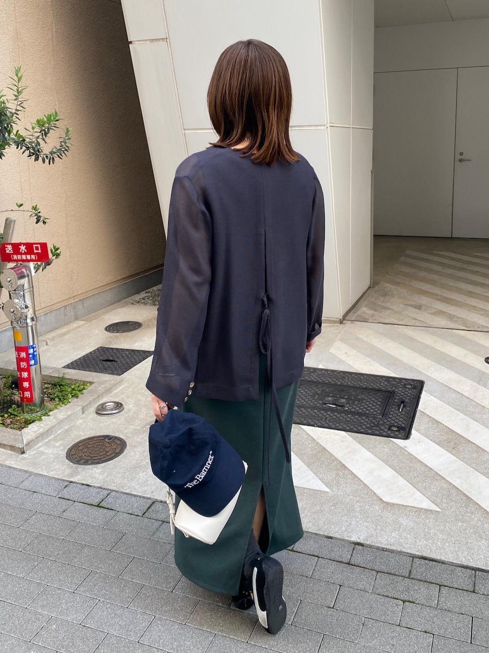 グレー系のテーラードジャケット、グリーン系のワンピースを着用したレディースの春コーディネートの2枚目の写真