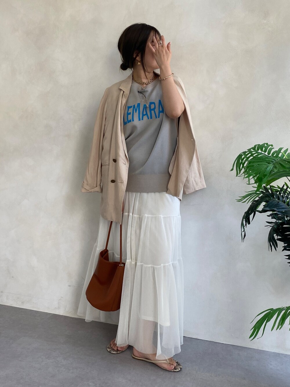 ベージュ系のテーラードジャケット、ホワイト系のスカート、ブラウン系のショルダーバッグを着用したレディースの夏コーディネートの2枚目の写真