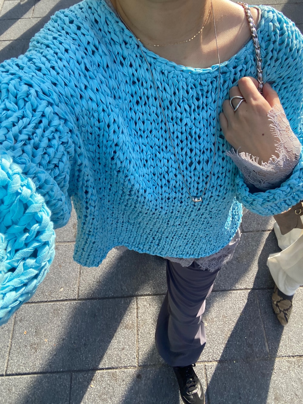 ブルー系のニット/セーター、グレー系のTシャツ/カットソー、グレー系のスラックスを着用したレディースの冬コーディネートの7枚目の写真