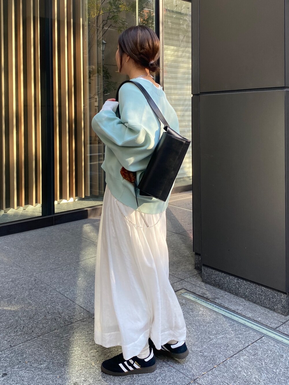 グリーン系のカーディガン/ボレロ、ホワイト系のスカートを着用したレディースの冬コーディネートの6枚目の写真