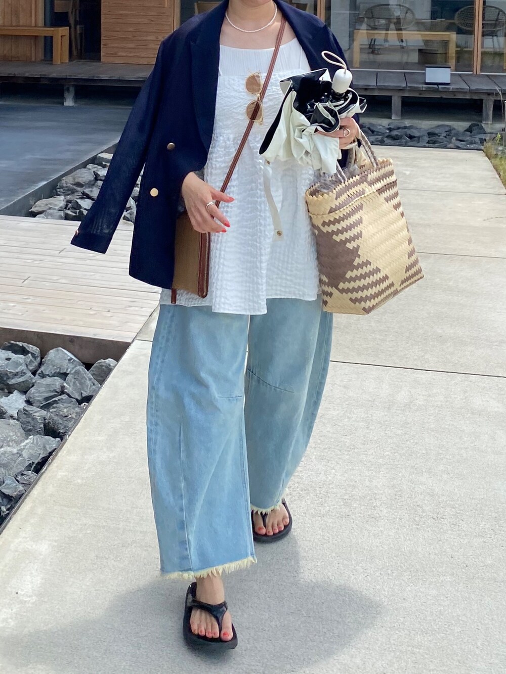 ブルー系のテーラードジャケット、ホワイト系のキャミソール、ブルー系のデニムパンツを着用したレディースの夏コーディネートの7枚目の写真