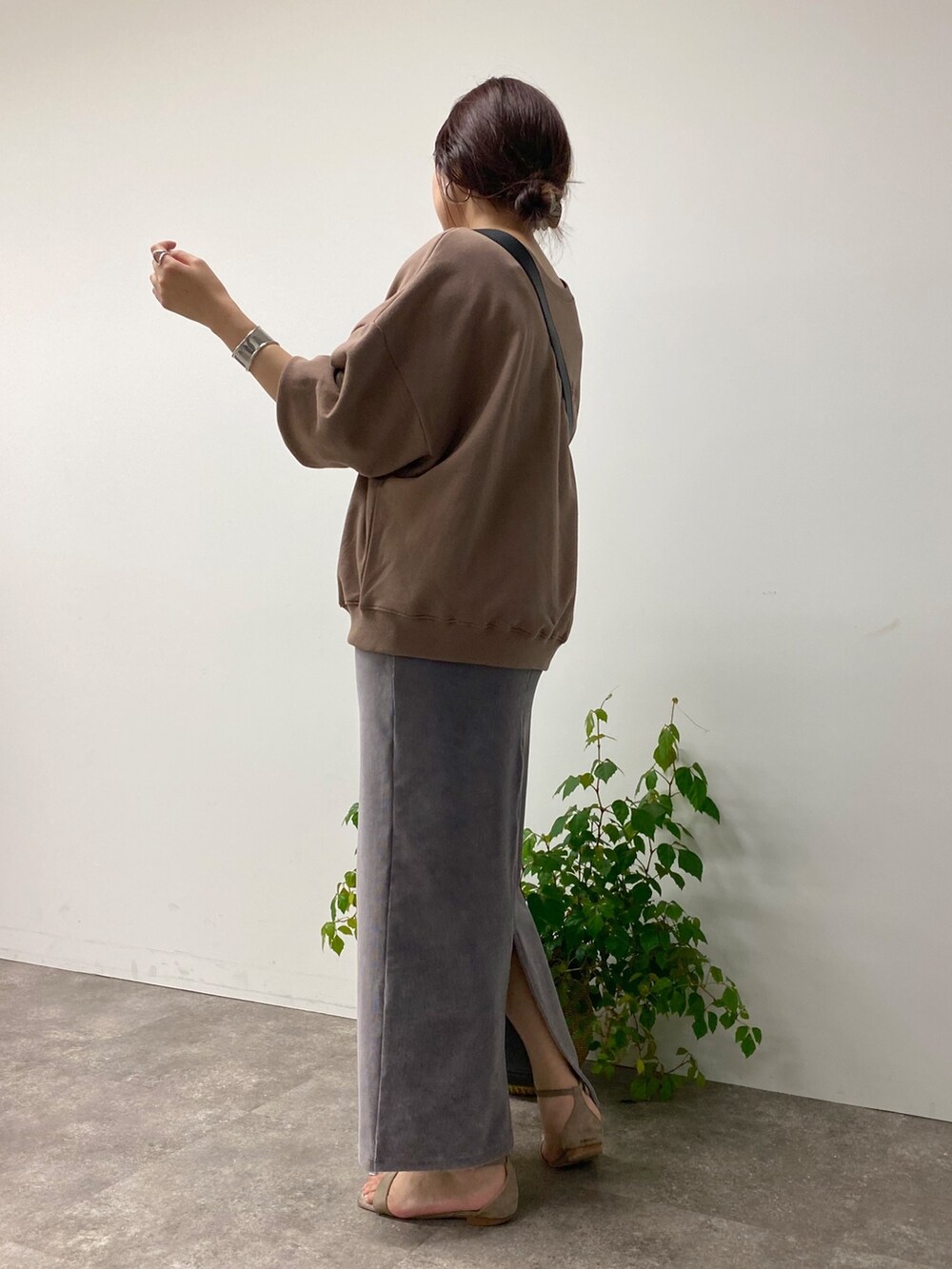 グレー系のスカート、ブラウン系のスウェット、ブラック系のバッグを着用したレディースの夏コーディネートの2枚目の写真